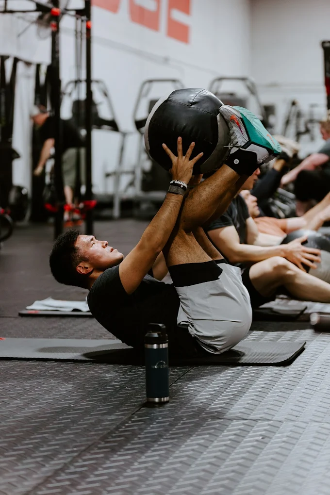 Male member performing a core workout with a medicine ball at Elite Edge Fitness in Chamblee