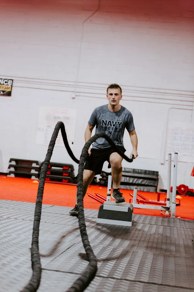 Male athlete performing battle rope workout for strength and endurance at Elite Edge Fitness